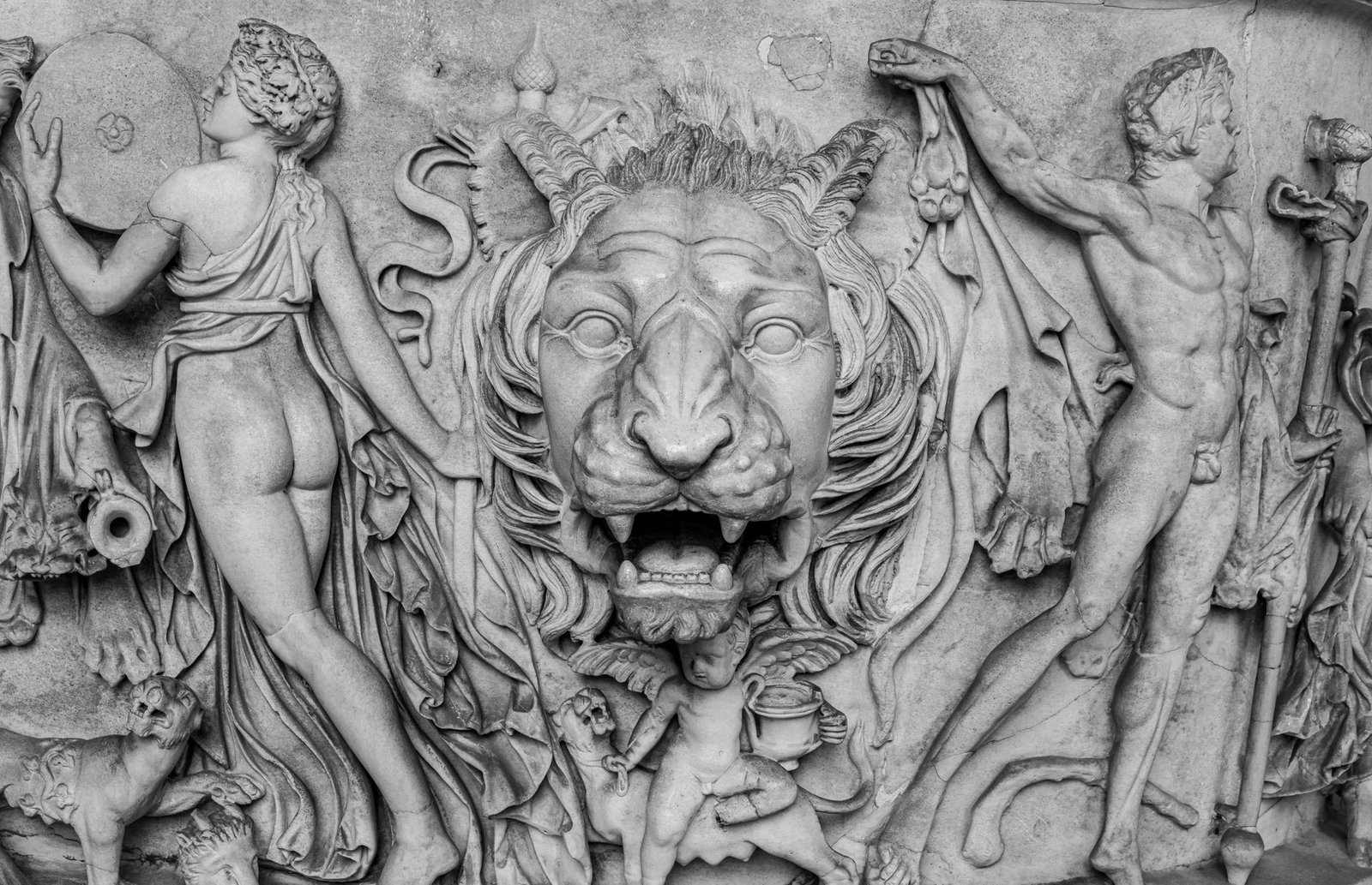 Ancient Roman marble relief of mythological figures beside a carved lion’s head