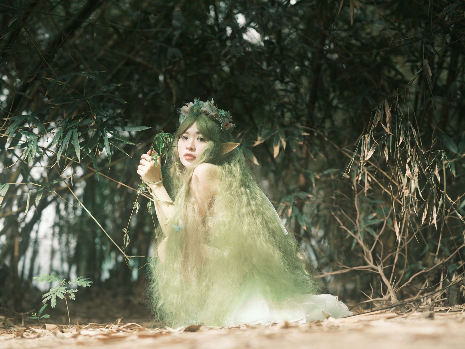 Fantasy woman with long green hair and elf ears standing in a forest, evoking an Irish folklore spirit and the Púca