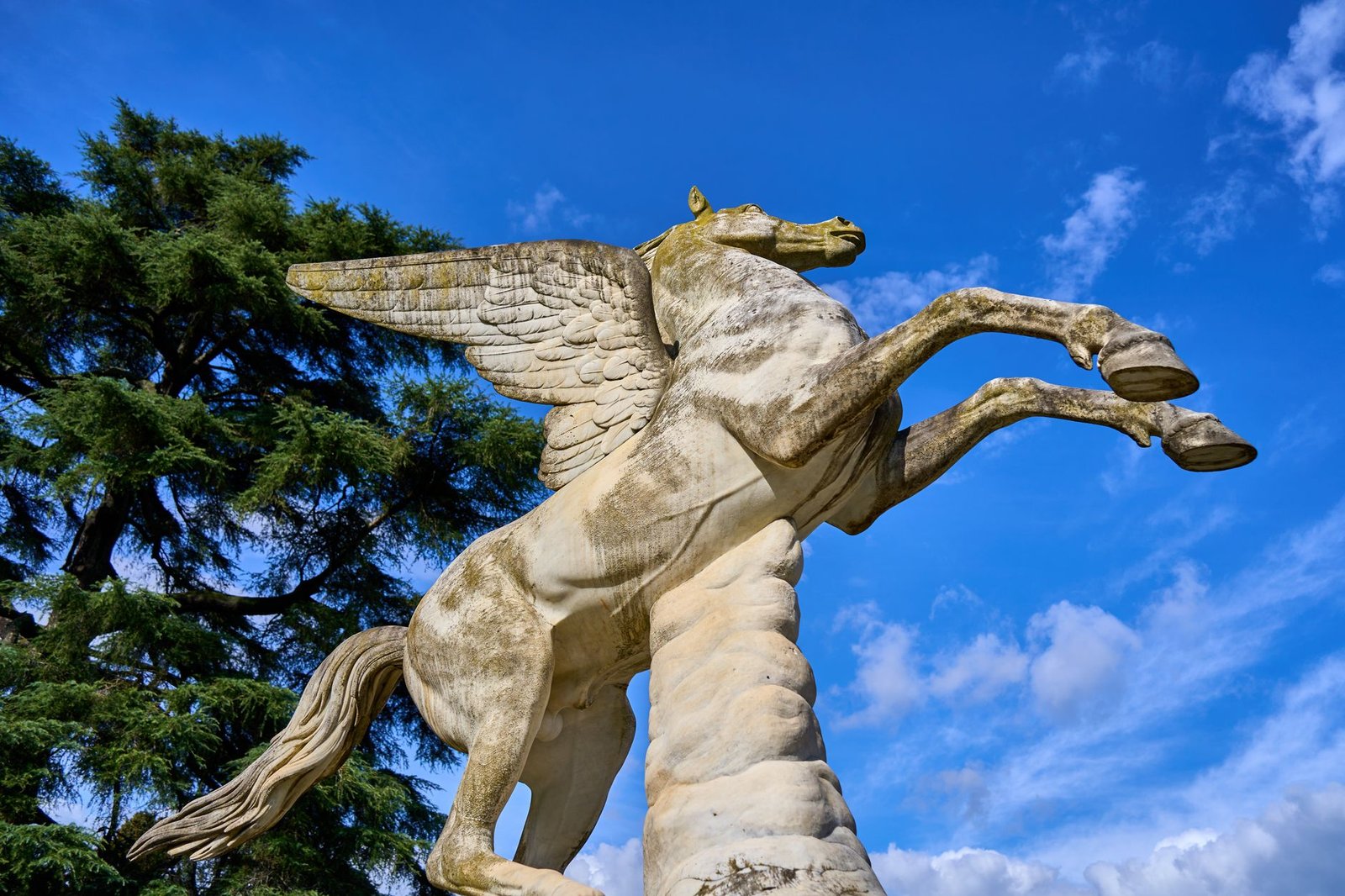 Stone statue of Pegasus, a winged horse from Greek mythology, against a blue sky