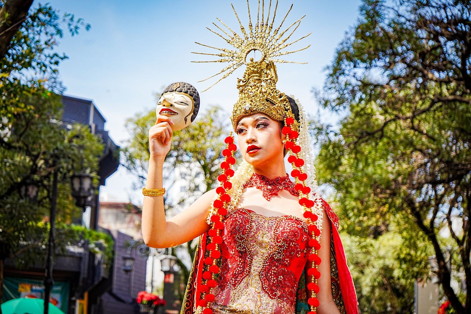 Traditional Balinese dancer in ornate costume and headdress performing outdoors