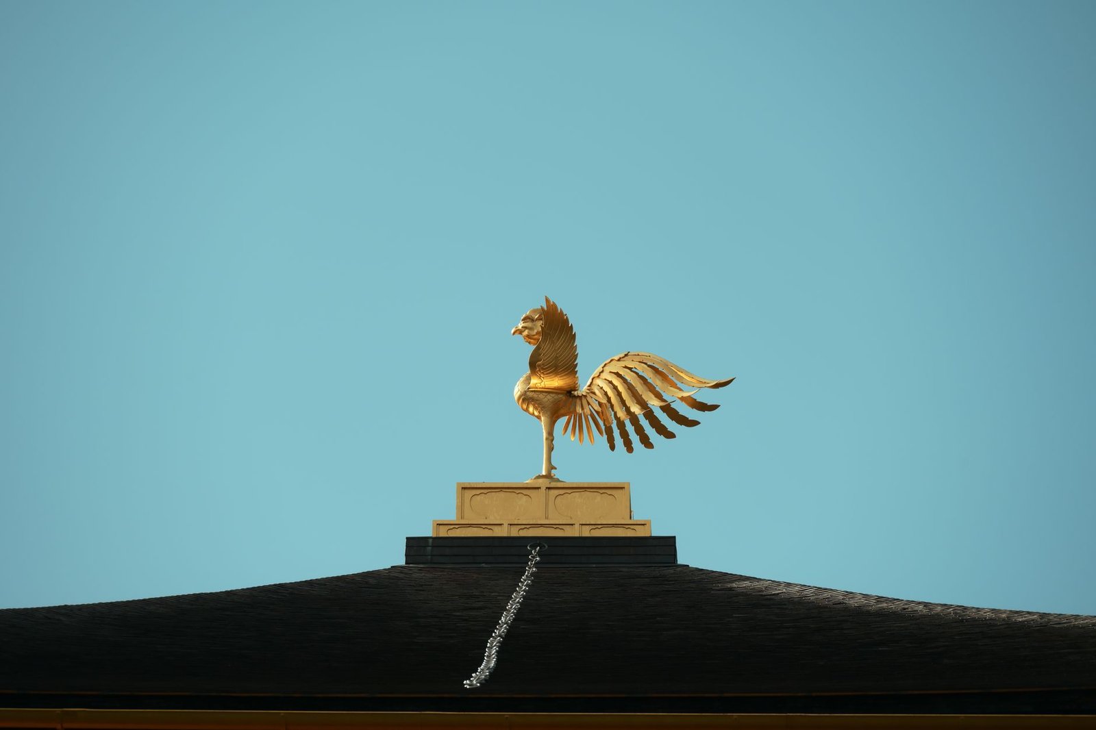Golden winged horse statue on a rooftop against a clear blue sky