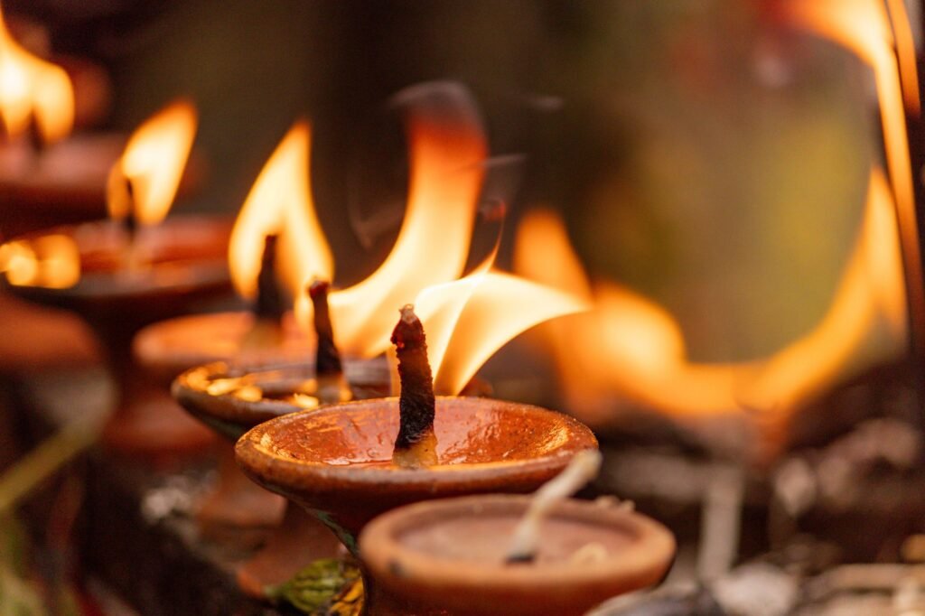 Close-up of traditional oil lamps with glowing flames in a spiritual setting, evoking Hestia’s sacred flame