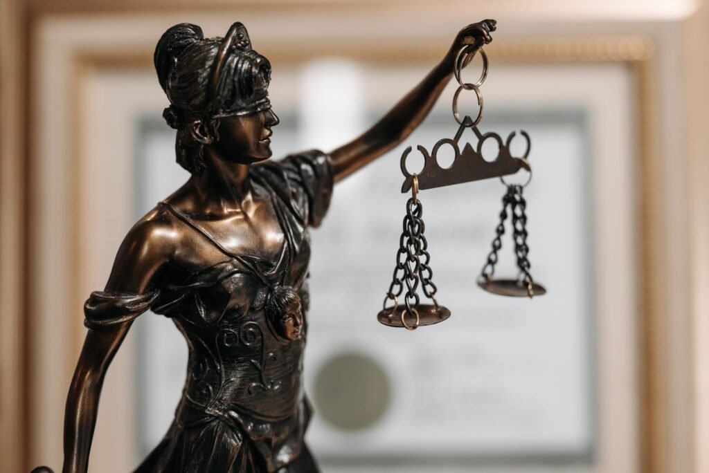 Bronze Lady Justice holding balanced scales with a blurred legal document in the background