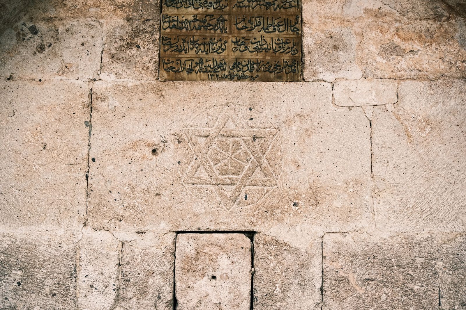 Ancient stone wall with a carved Star of David and an inscription plaque