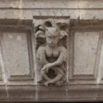 Close-up of a stone facade carving showing a mythical creature on a building exterior