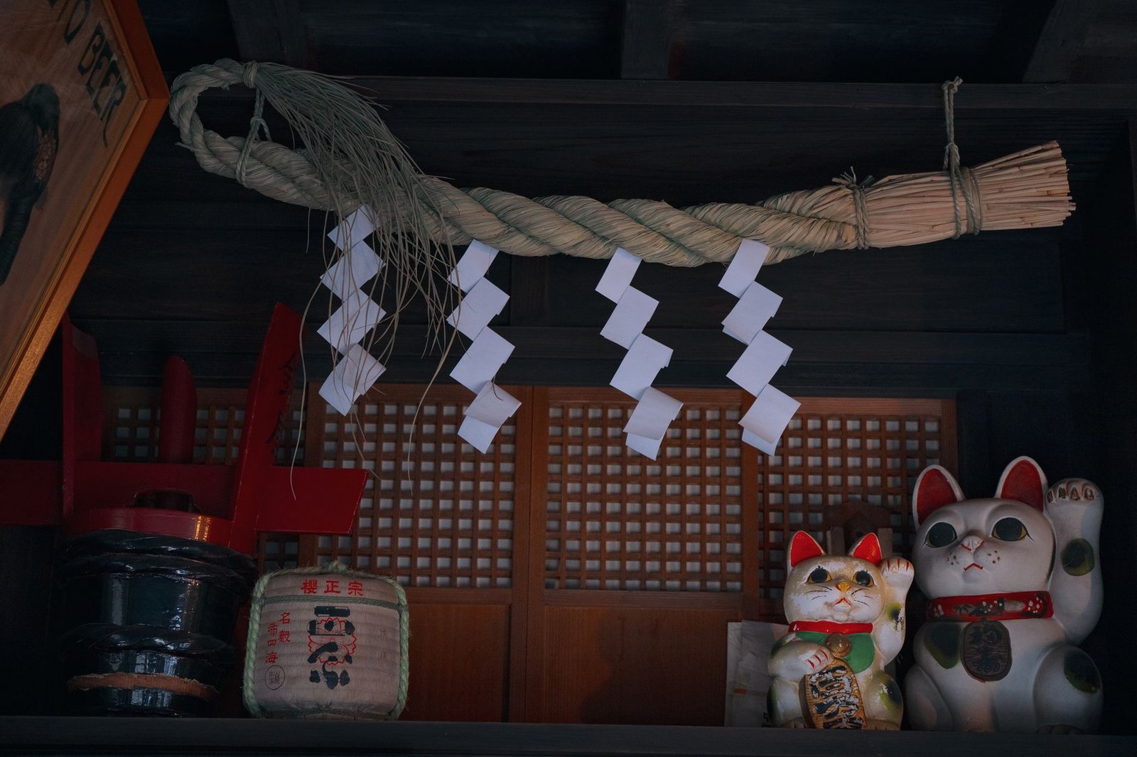 Shimenawa rope at a Japanese shrine with maneki-neko lucky cat figurines and decorative sacred ornaments