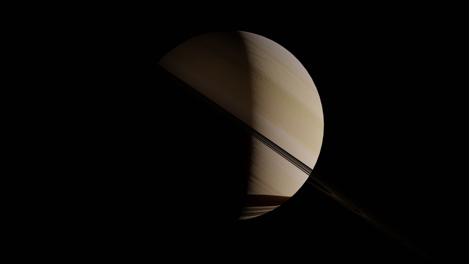 Saturn with partially illuminated rings against a dark background