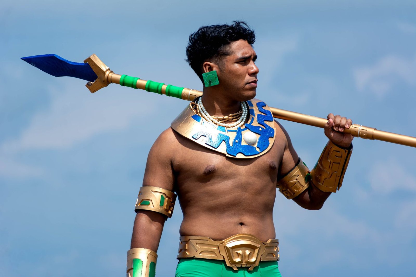Man dressed as an ancient warrior holding a spear against a blue sky background