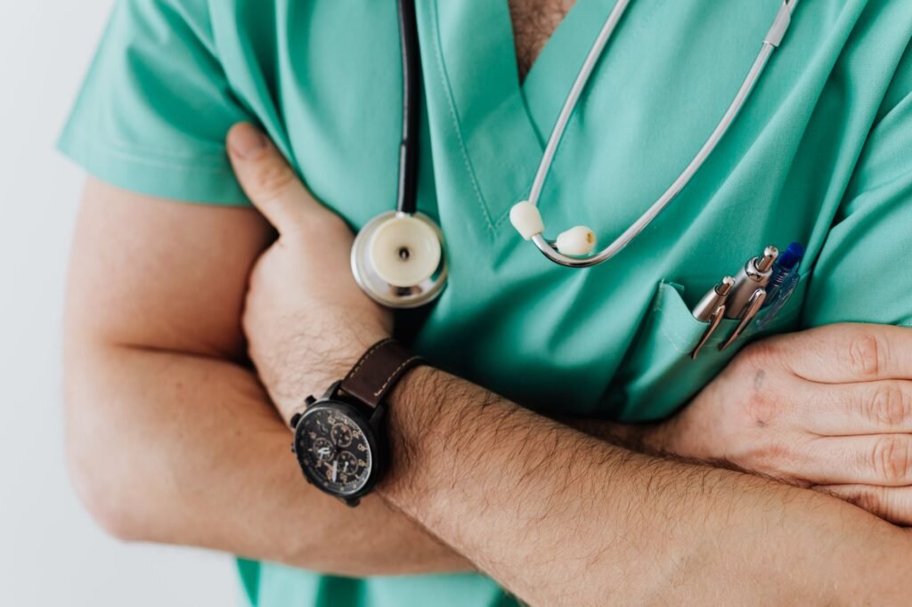 Healthcare professional in green scrubs with stethoscope, arms crossed, symbolizing the Staff of Asclepius theme