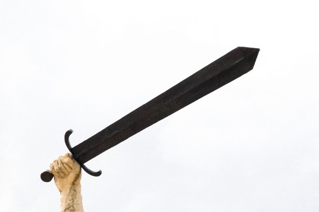 Hand holding a large black sword against a white background