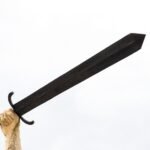 Hand holding a large black sword against a white background