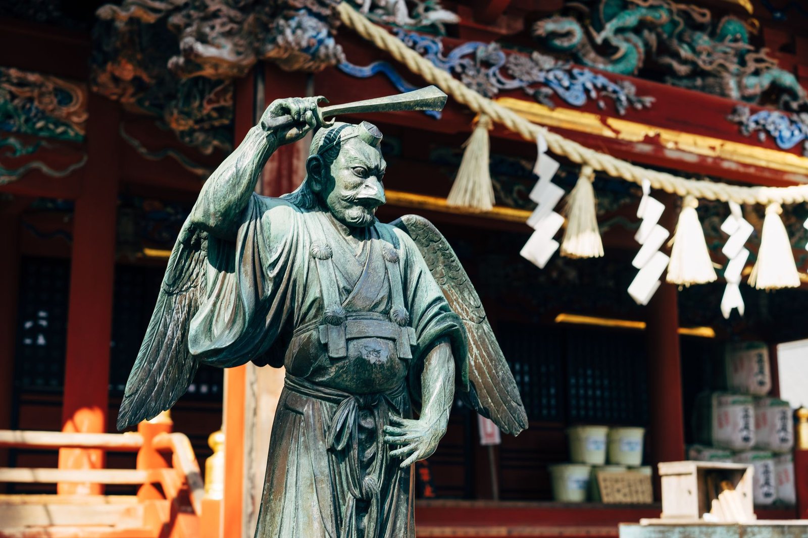 Statue of a warrior angel holding a sword in front of a traditional Japanese shrine