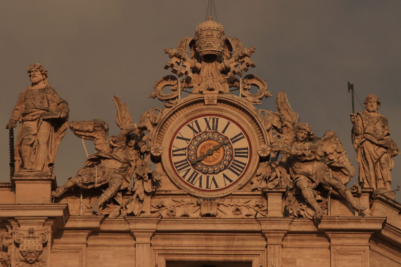 Ornate historic clock with Roman numerals on a classical facade, flanked by statues of the Horatii and the Curiatii legend