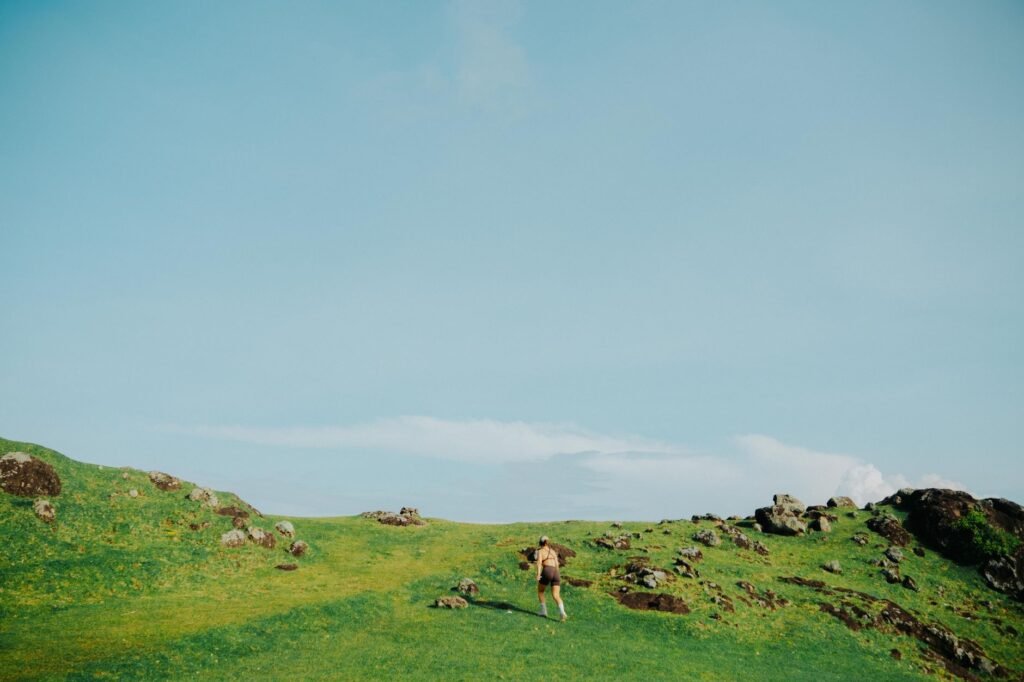 Person running on a green grassy hill under a clear blue sky, evoking Diarmuid and Gráinne's pursuit