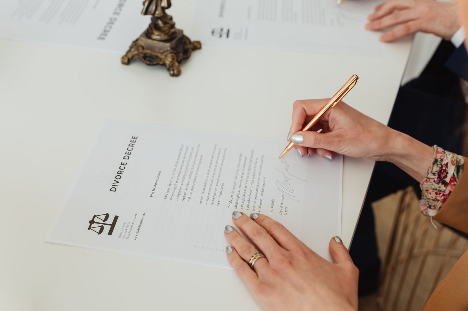 Person signing a legal contract on a white desk with a pen, representing the Roman gods Dii Consentes.
