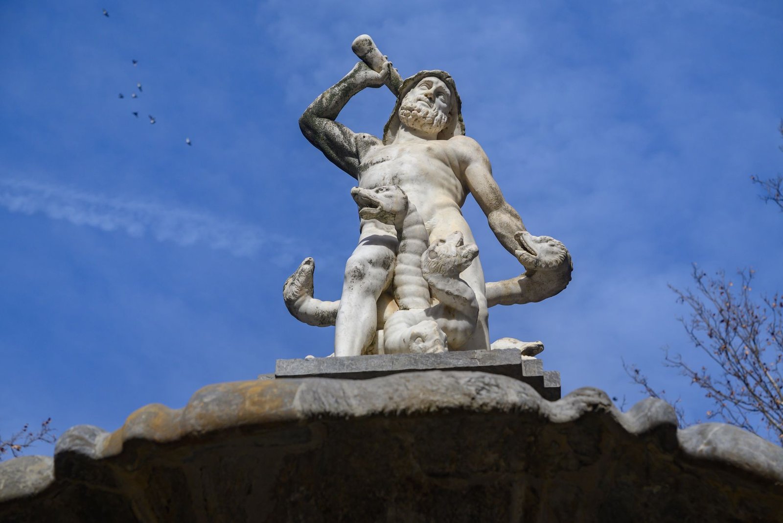 Statue of Heracles holding a club against a blue sky background