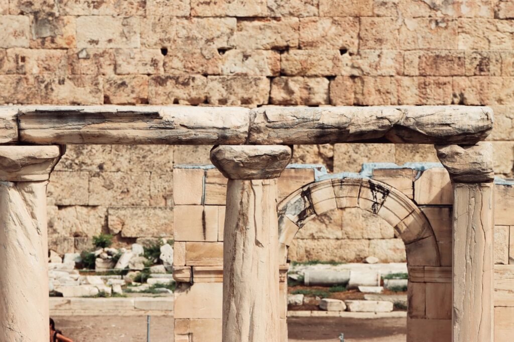 Ancient stone columns and archway ruins against a weathered brick wall