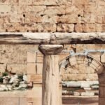 Ancient stone columns and archway ruins against a weathered brick wall