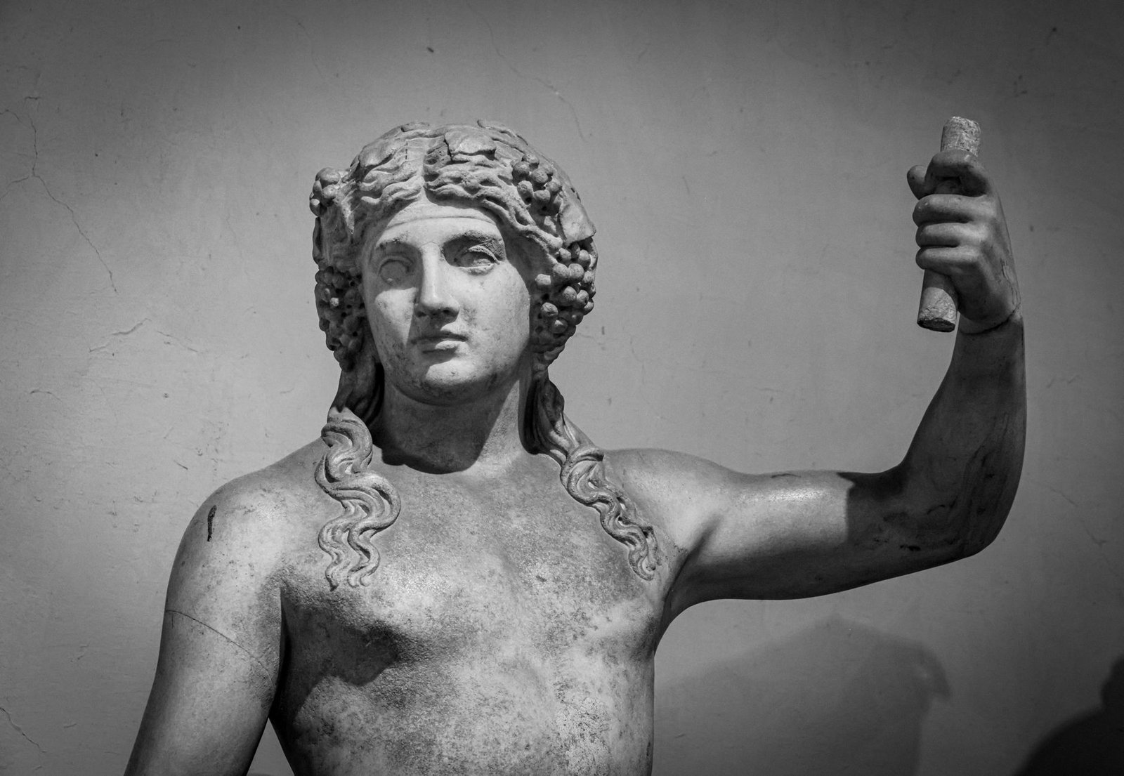Black and white photo of a Roman marble statue of a male figure holding an object, representing Venus theme