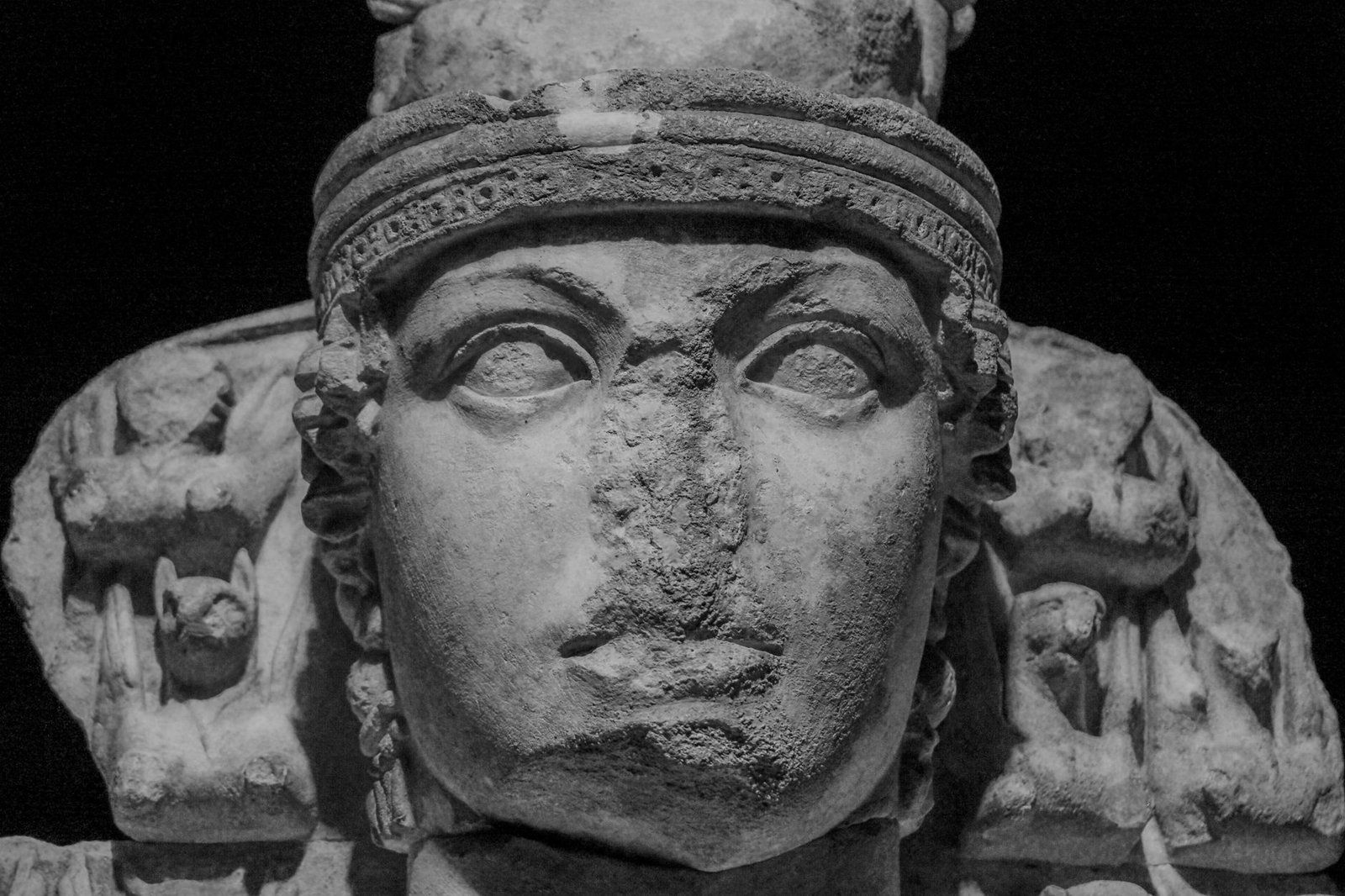 Ancient stone sculpture of a Roman goddess face with intricate headgear and side figures