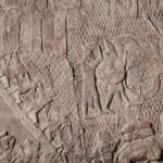 Ancient Assyrian stone relief of a battle with soldiers, chariots, and animals, showing a war scene in Latium-like conflict