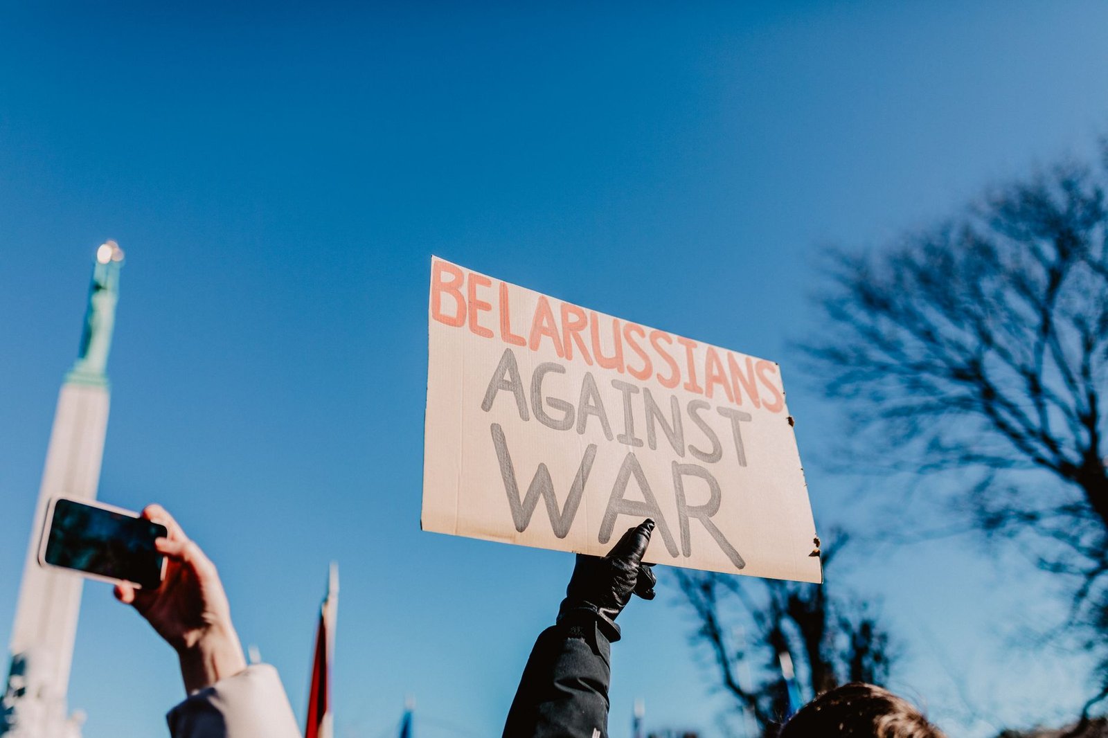 Protesters hold a "Belarussians Against War" sign at an outdoor demonstration.