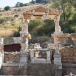Ancient stone ruins of a Roman archaeological site surrounded by green vegetation and trees