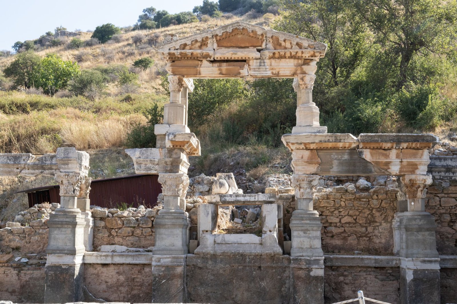 Ancient stone ruins of a Roman archaeological site surrounded by green vegetation and trees