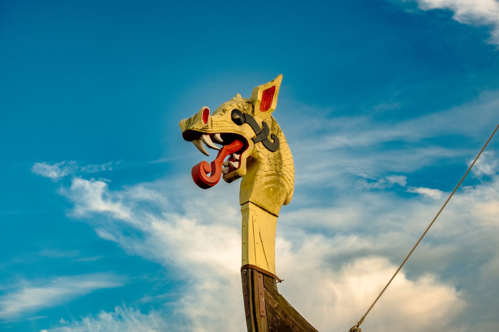 Dragon-headed Viking ship prow under a blue sky, evoking Fimbulwinter in Norse mythology