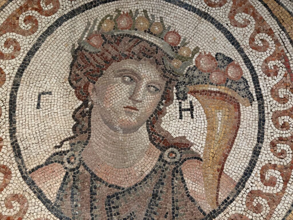Ancient mosaic of a crowned figure holding a cornucopia in Greek mythology