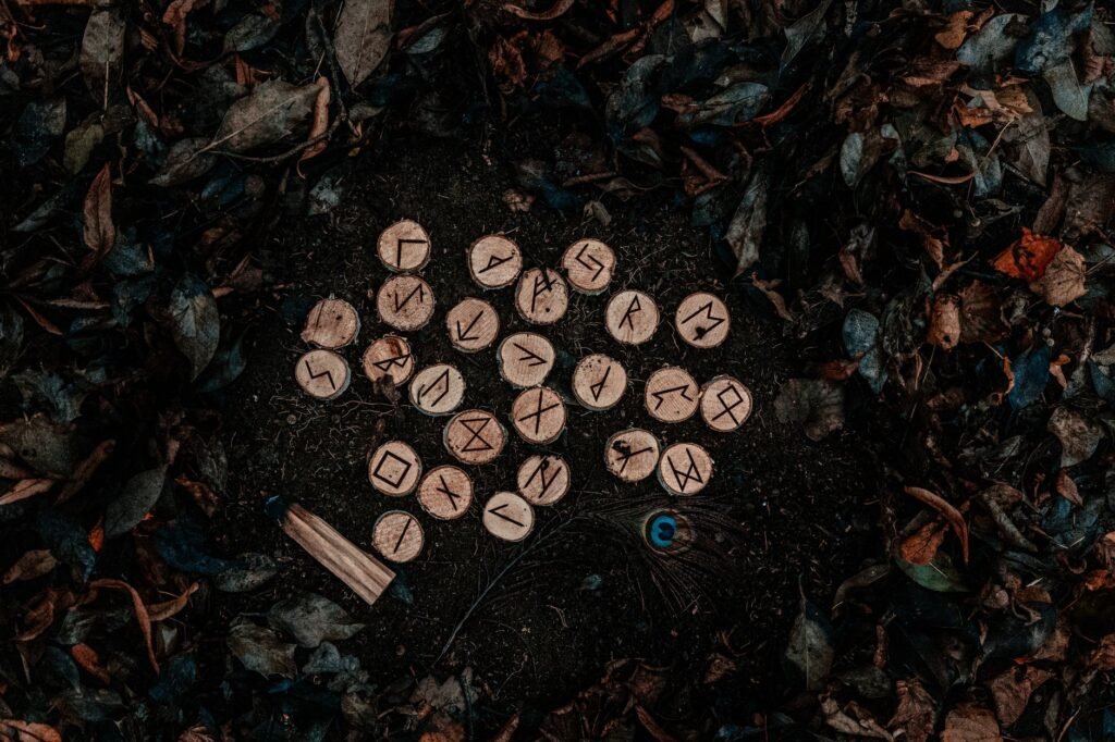 Wooden Elder Futhark rune stones on a dark forest floor with fallen leaves