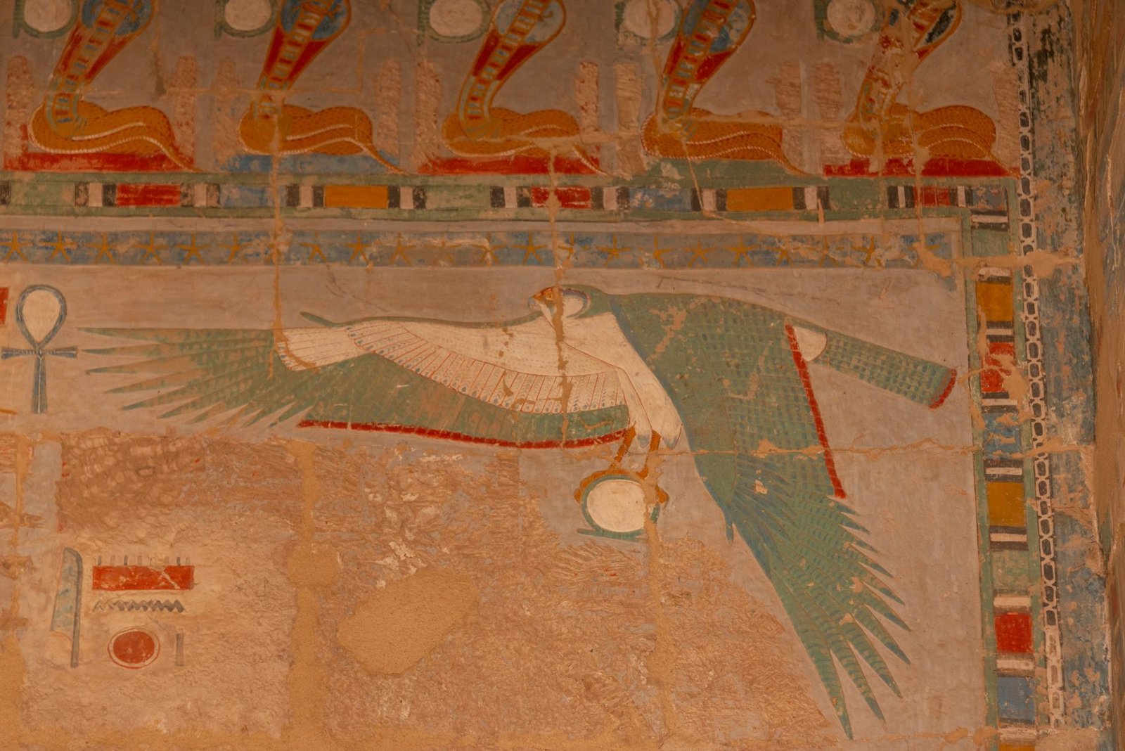 Ancient Egyptian wall painting of Horus, a falcon-headed god, shown in profile with traditional headdress and jewelry