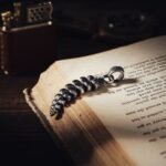 Vintage silver feather pendant on an open old book with a leather lighter behind it