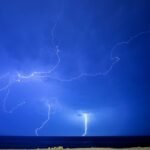 Lightning over the ocean at night, evoking the thunderbolt of Zeus in Greek mythology