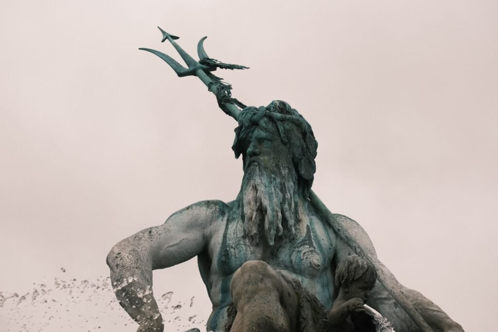 Neptune Fountain statue holding the trident of Poseidon against a cloudy sky