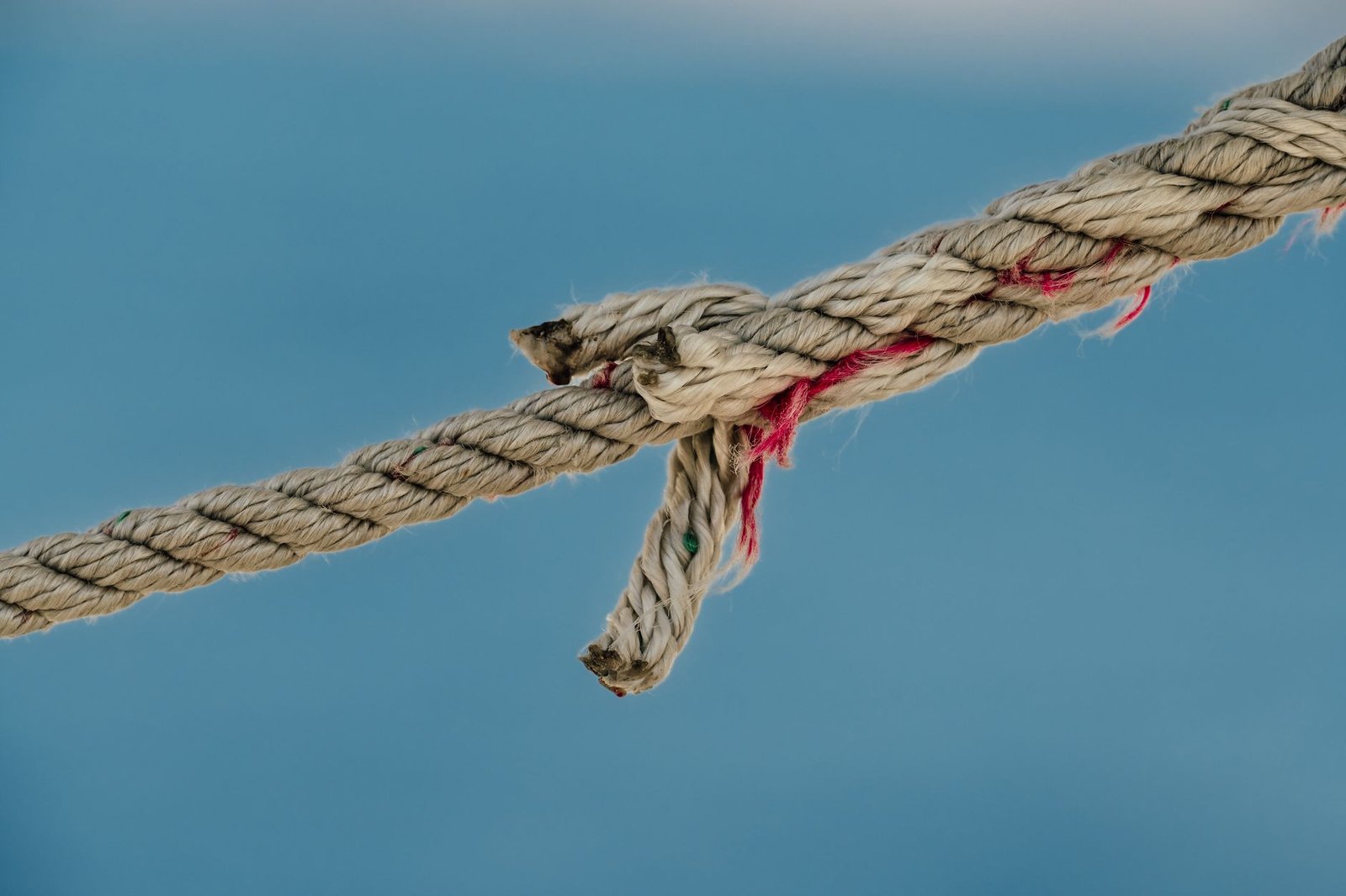Frayed rope close-up on a blue background, resembling the Tyet knot from Egyptian mythology