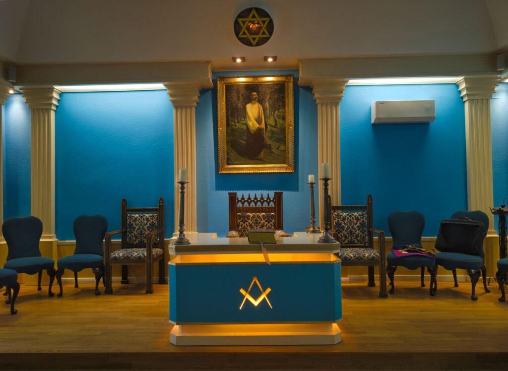 Masonic lodge room interior with symbolic decor, seating, and a central compass-like emblem