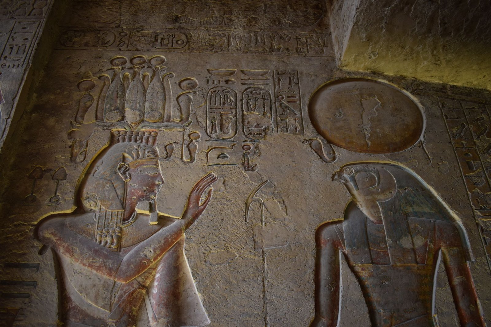 Ancient Egyptian temple carvings of Hathor and other deities with hieroglyphics on a stone wall