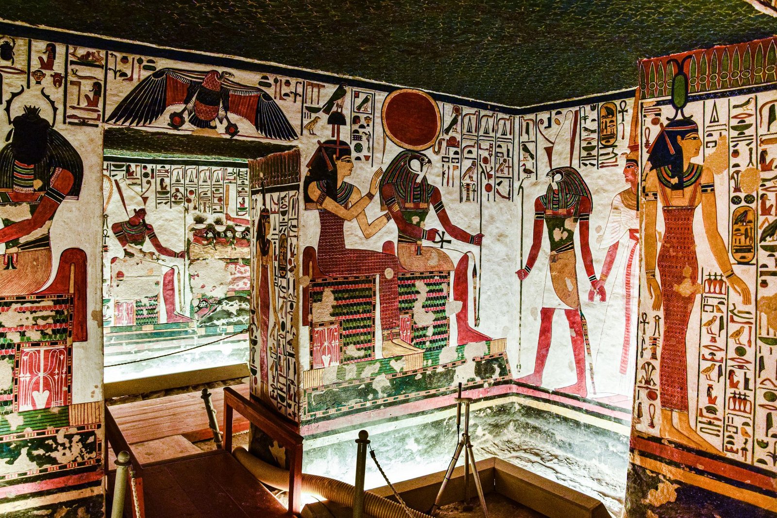 Ancient Egyptian tomb interior with colorful hieroglyphics and wall paintings depicting Osiris, the god of the dead