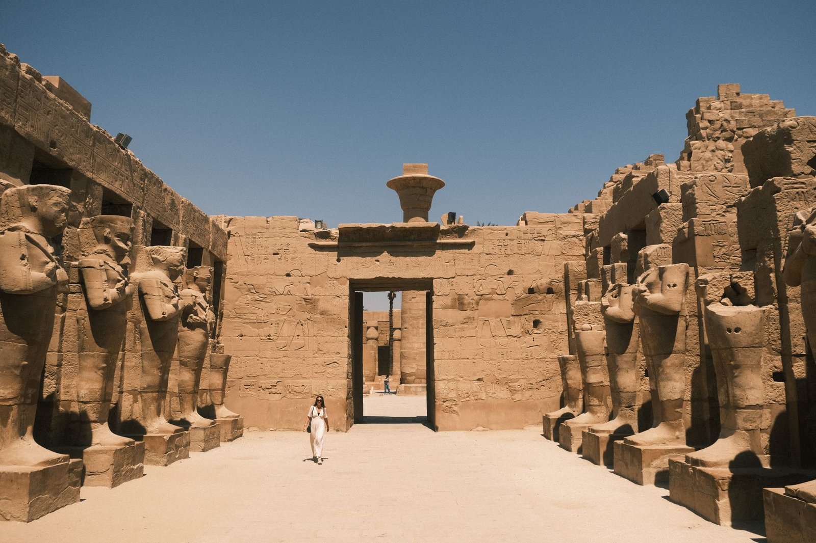 Ancient Egyptian temple ruins with towering statues beneath a clear blue sky, evoking Amun Ra as king of the gods