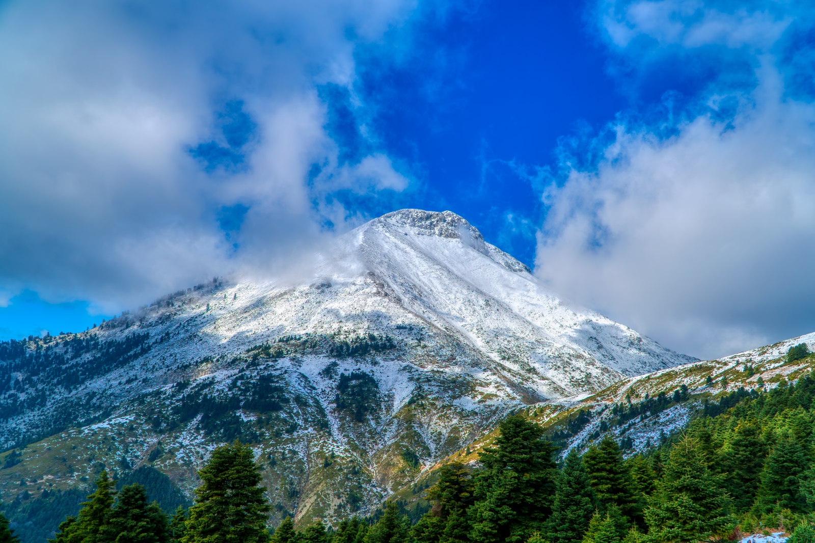 Snow-capped Mount Olympus peak under a bright blue sky, symbolizing Zeus, King of the Greek gods