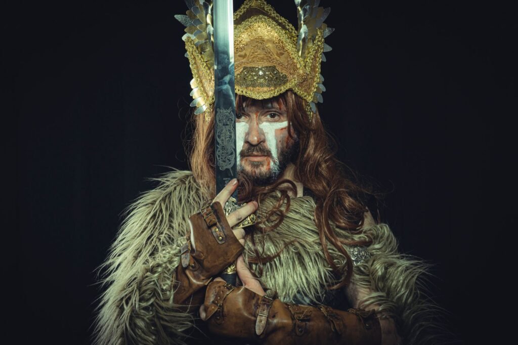 Viking warrior in fur clothing and helmet holding a sword, representing who is the king of the Norse gods