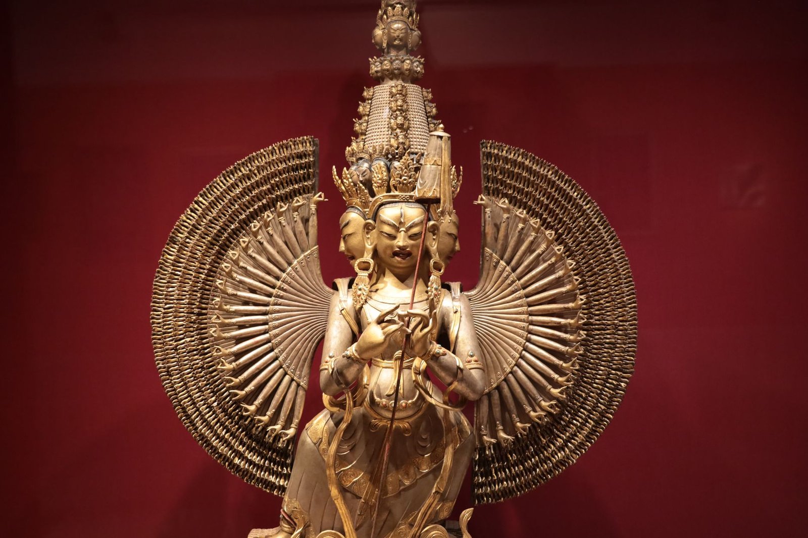 Golden multi-armed deity statue against a red background, representing Amaterasu as supreme deity