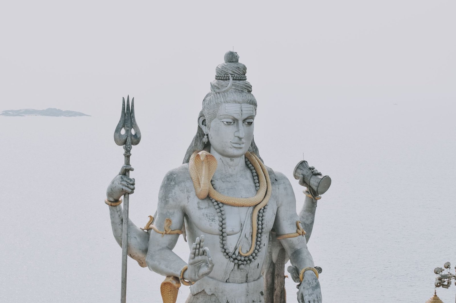 Statue of Lord Shiva holding a trident with a serene ocean in the background