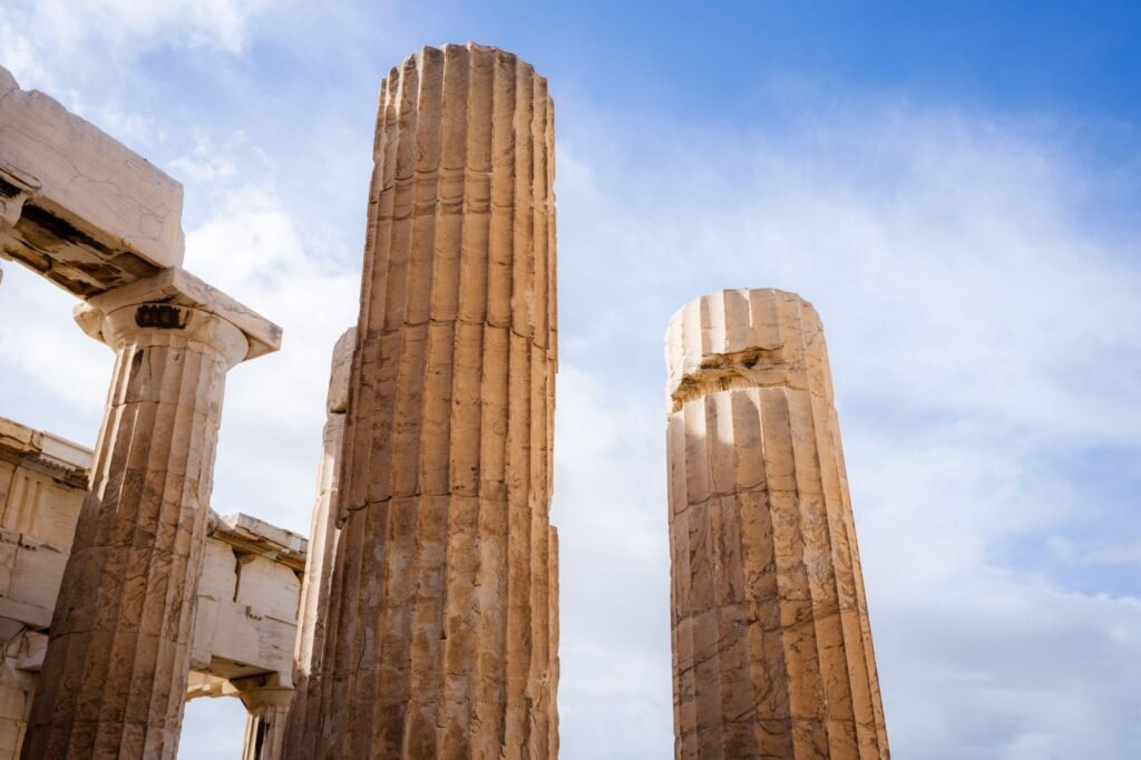 Ancient Greek temple columns under blue sky, evoking the Twelve Olympians and Dionysus’s place among them