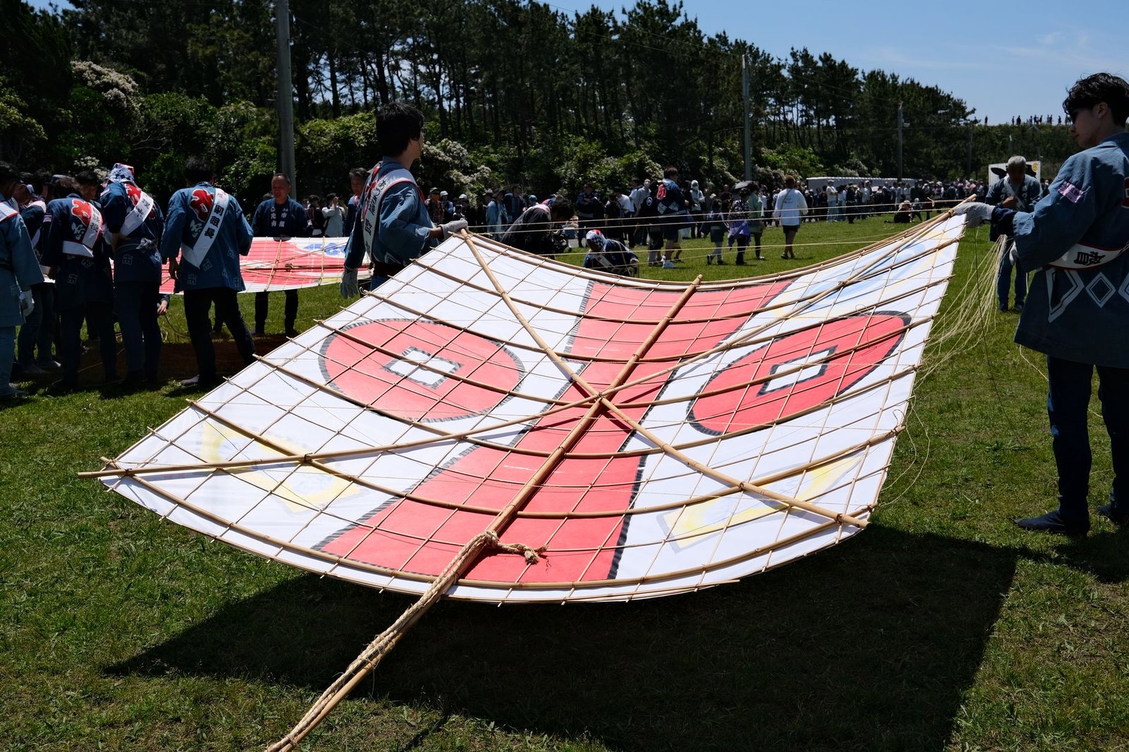 Traditional Japanese kite with red and white design being prepared for flying at an outdoor festival