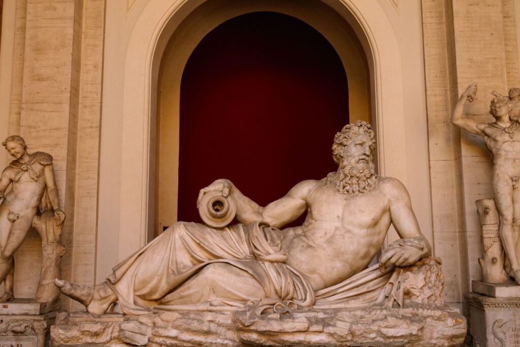 Ancient Roman marble statue of a reclining bearded man holding a scroll in a museum display, representing Zeus and Danae myth