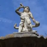 Statue of Balor, a muscular mythological figure holding a club against a blue sky